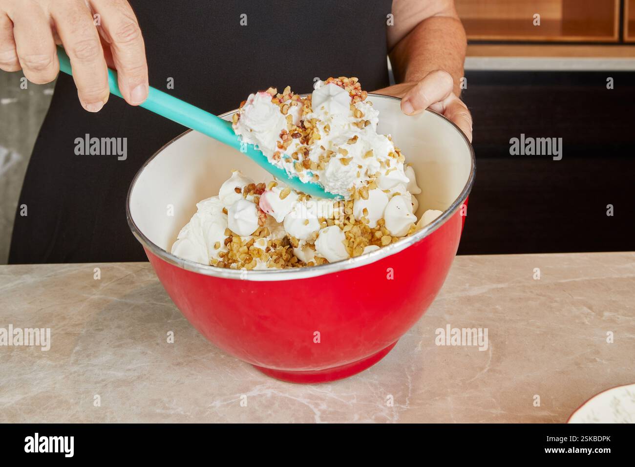 Une bouteille versant de l'extrait de vanille dans un mélange de dessert, rehaussant la saveur dans une atmosphère de cuisine confortable. Banque D'Images