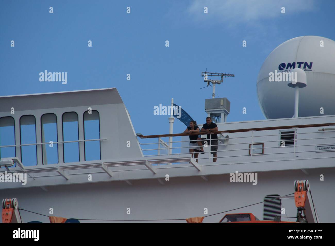 La photo capture un moment de détente et de plaisir alors que deux personnes se tiennent debout sur le pont d'un bateau de croisière, regardant l'océan. Le logo MTN est visible o Banque D'Images