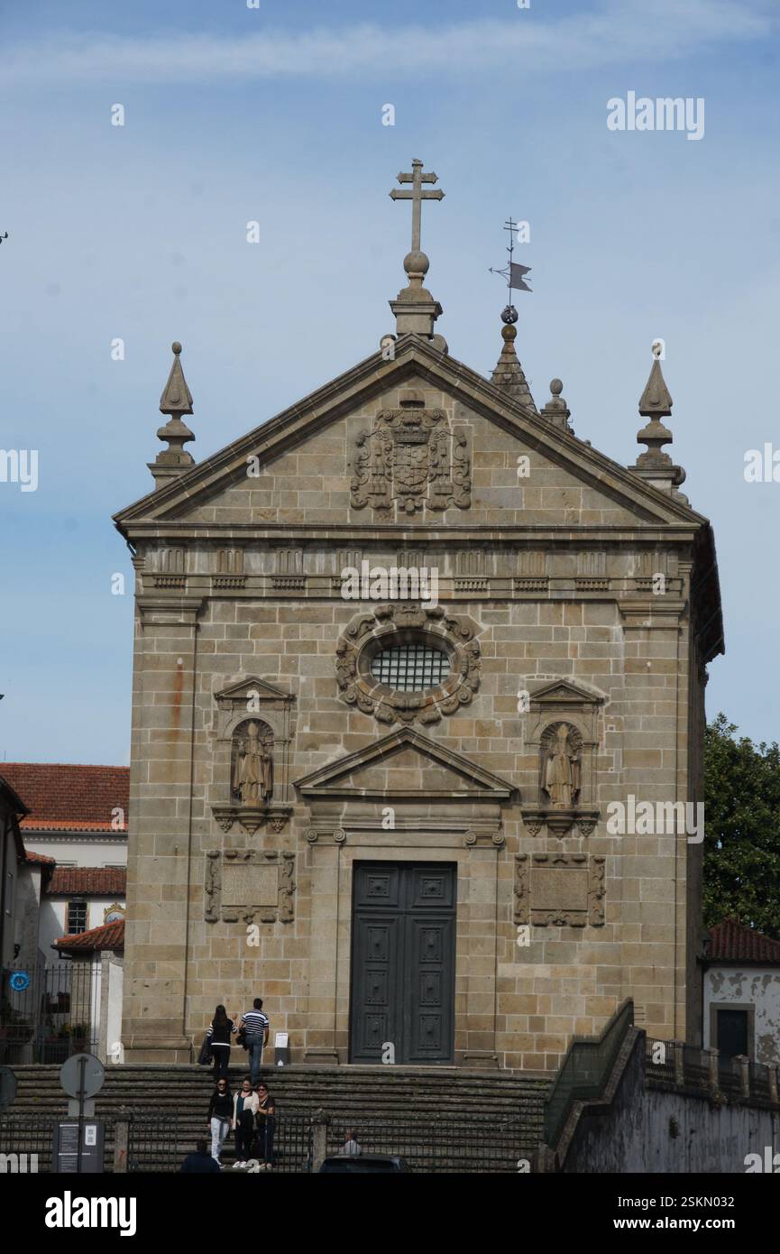 Façade d'église en pierre à Braga, Portugal. Des sculptures complexes, des statues et une croix centrale ornent la pierre altérée. Un témoignage de siècles de foi Banque D'Images