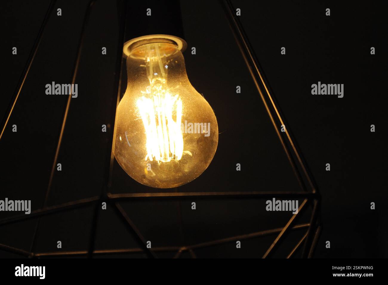 gros plan dans une ampoule edison avec une lumière jaune et un peu de poussière le soulèvent Banque D'Images