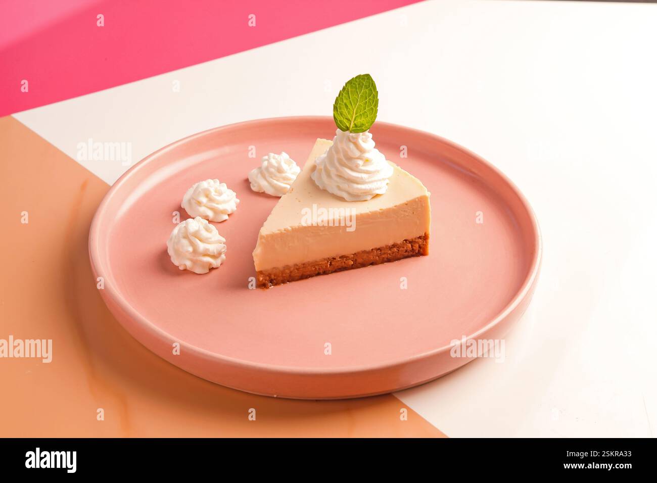 Femme chef plaçant la feuille de menthe sur un tourbillon de crème sur le gâteau au fromage. Banque D'Images