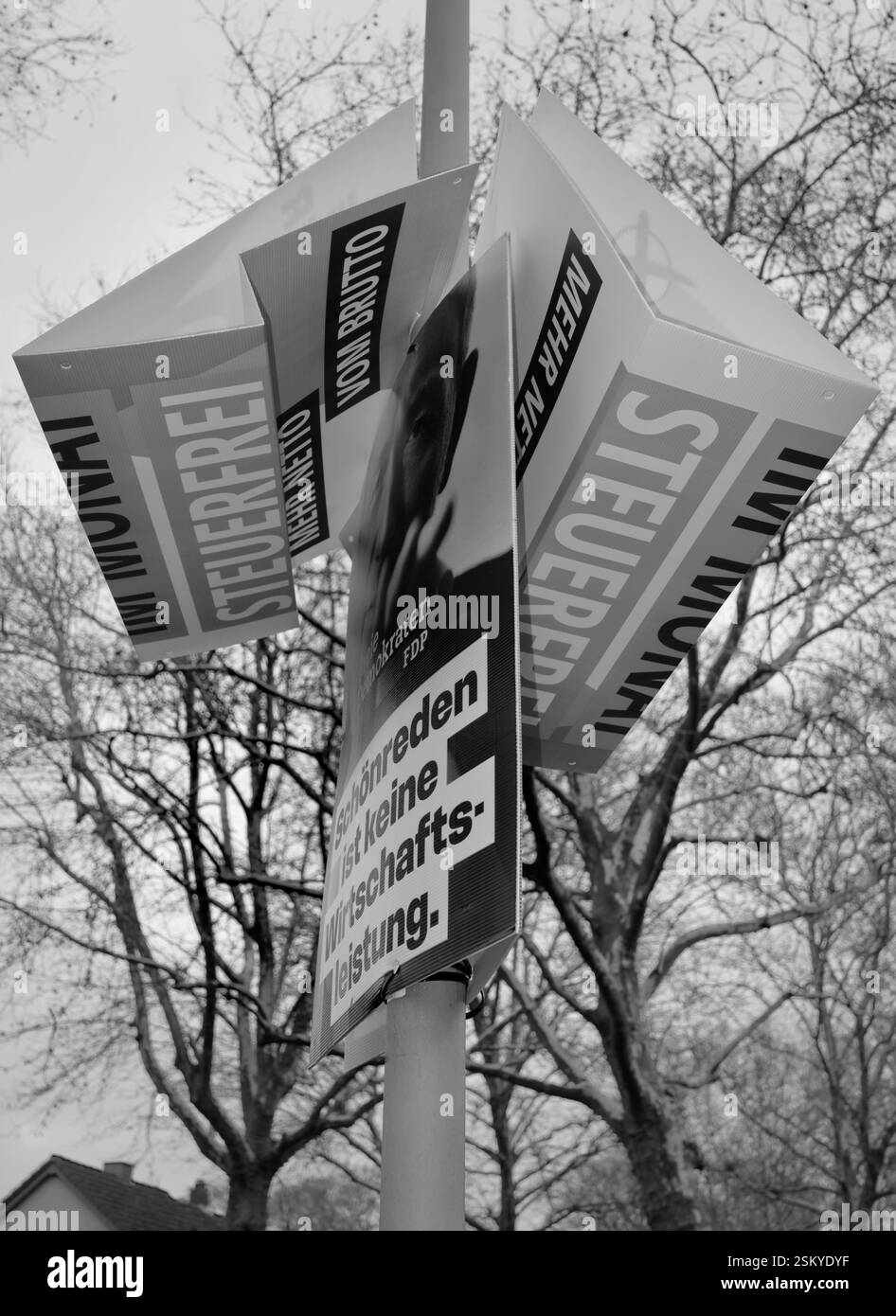 Des affiches électorales pour les élections législatives du Bundestag allemand 2025 sont accrochées de manière tordue à un lampadaire représentant de mauvais résultats électoraux,b&w Banque D'Images