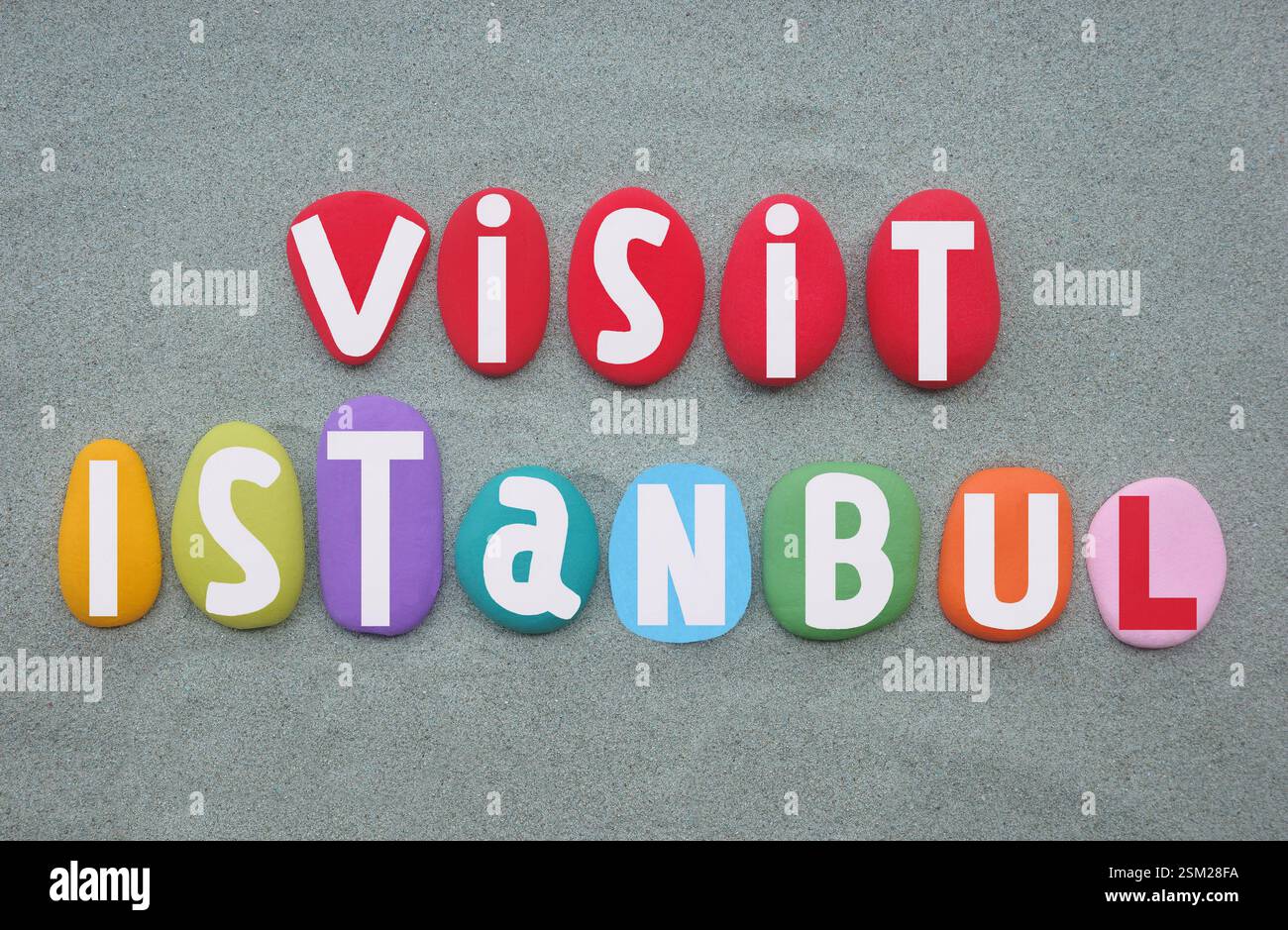 Visitez Istanbul, design de logo créatif composé de lettres en pierre peintes à la main multicolores sur du sable vert Banque D'Images