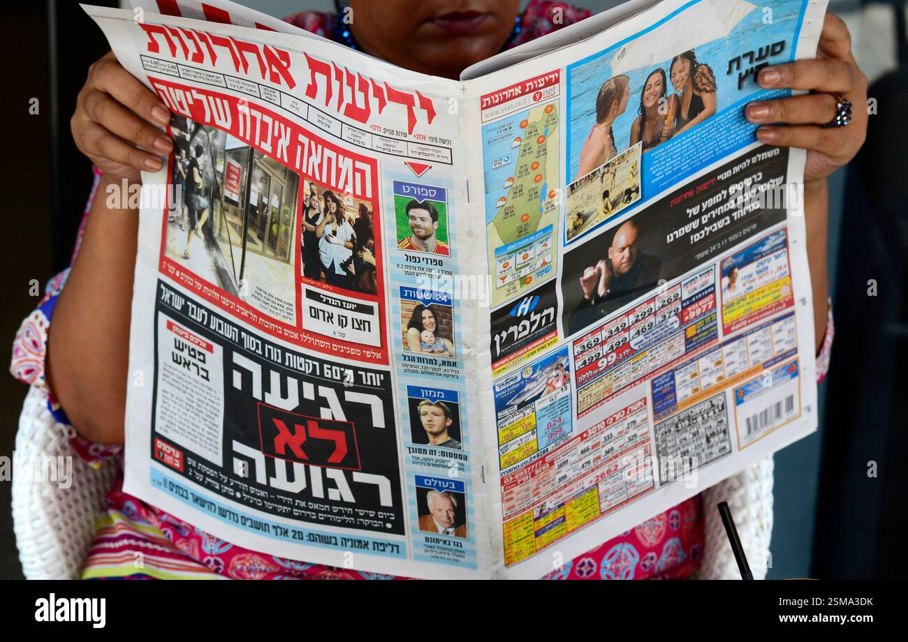 Une femme lisant le populaire journal Yedioth Aharonoth à tel Aviv, Israël. Banque D'Images
