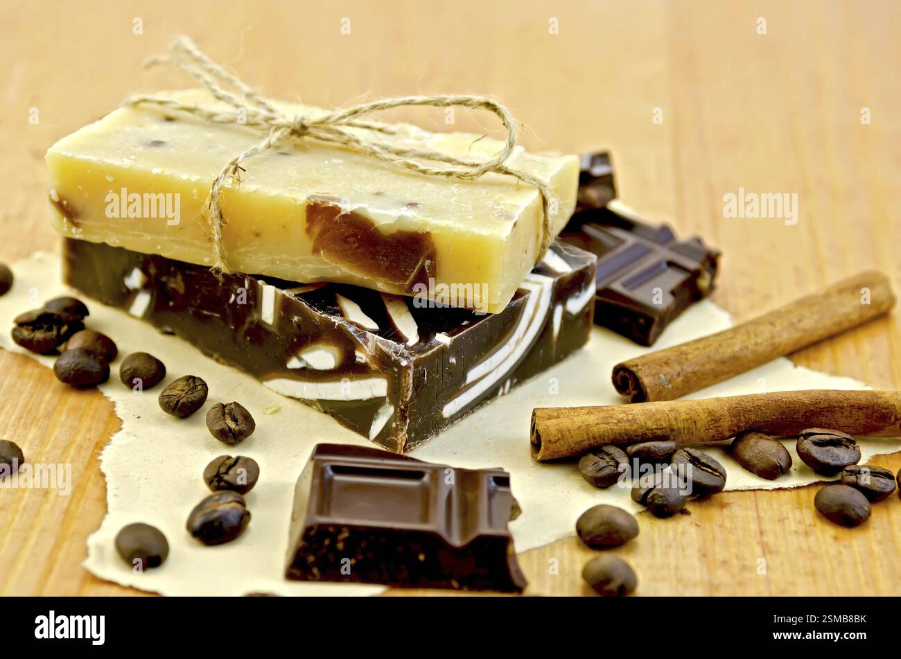 Deux barres de savon fait maison, liés avec de la ficelle, le chocolat, la cannelle, les grains de café sur vieux papier sur l'arrière-plan de planches en bois Banque D'Images