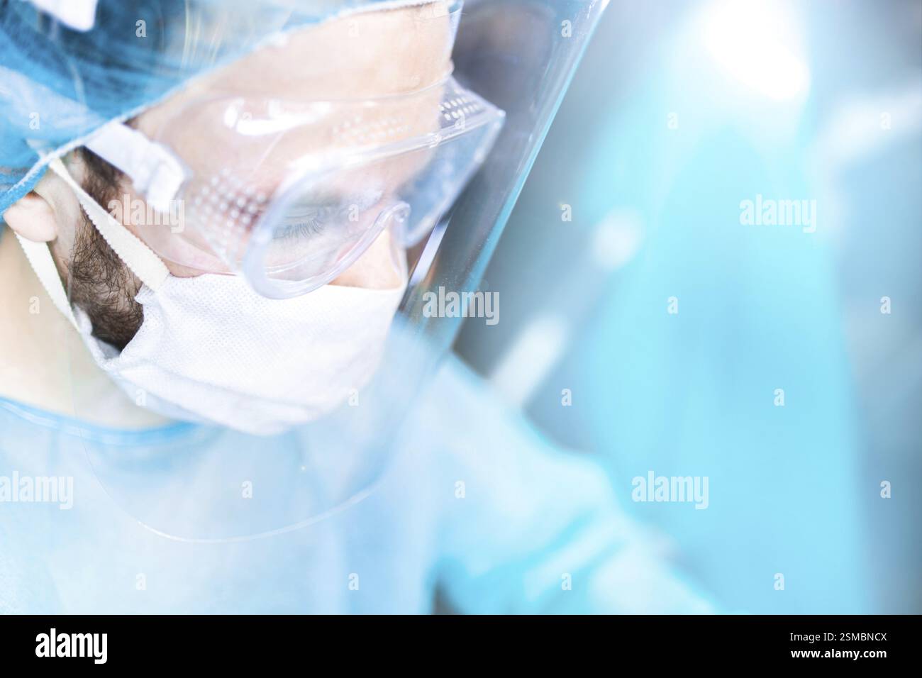 Vue de côté d'une personne en équipement médical avec lumière parasite, se concentrant sur une tâche en bleu et blanc Banque D'Images