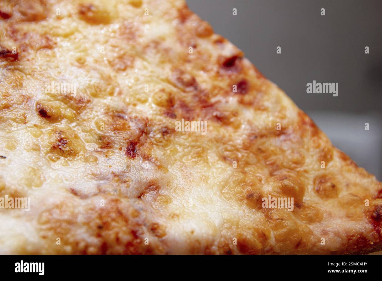Gros plan d'une tranche de pizza au fromage avec une croûte brune dorée Banque D'Images