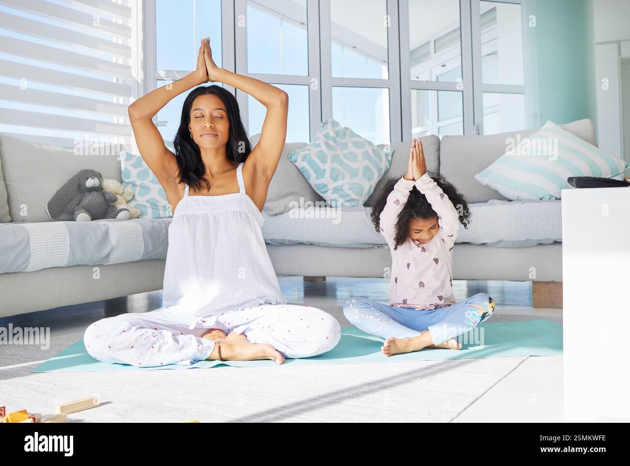 Mère, enfant et exercice de yoga à la maison, se lier ensemble et forme physique matinale pour la sensibilisation. Namaste, maman et fille dans le salon pour la méditation Banque D'Images
