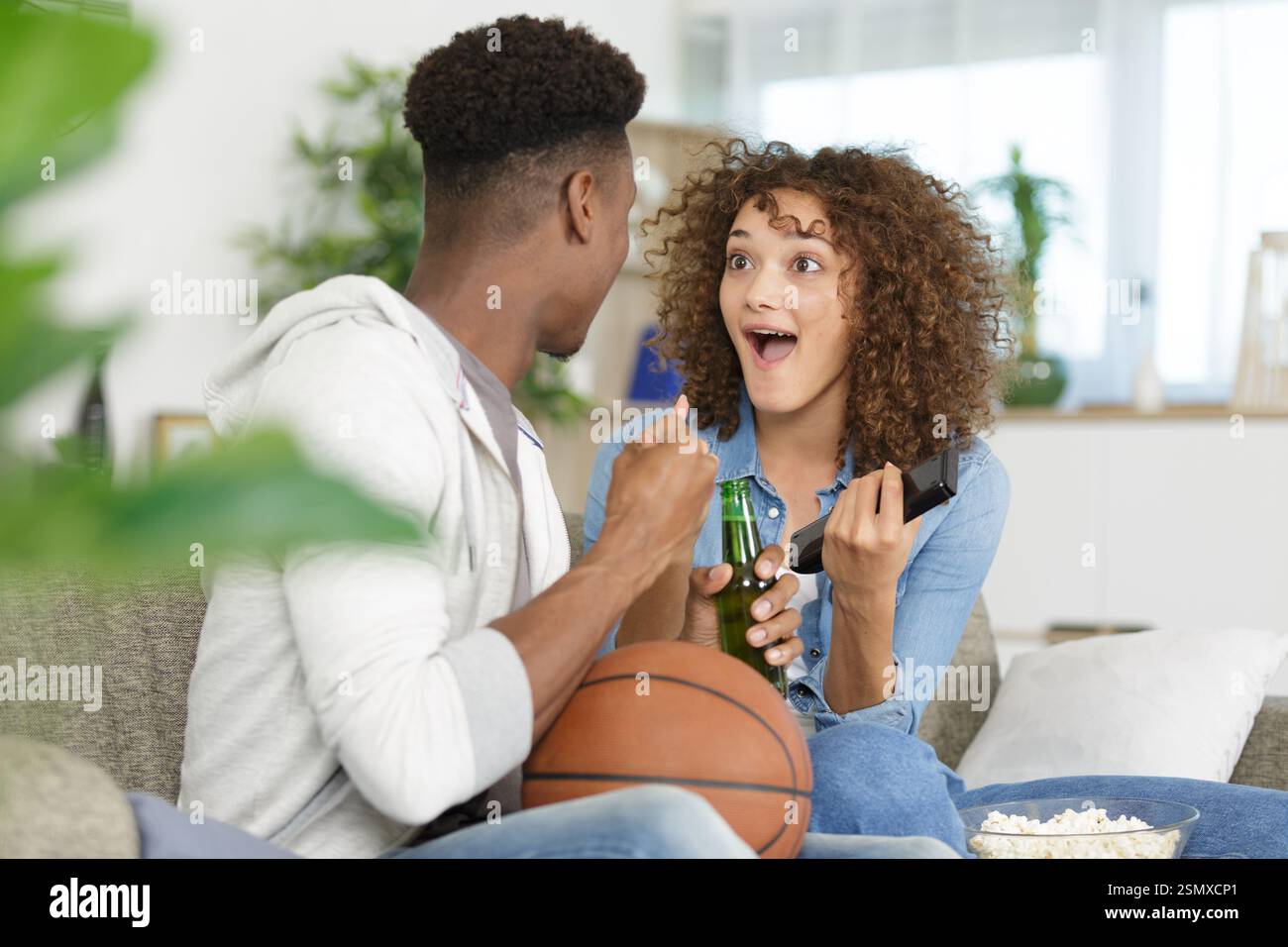 couple mixte buvant de la bière et encourageant le match de basket-ball Banque D'Images