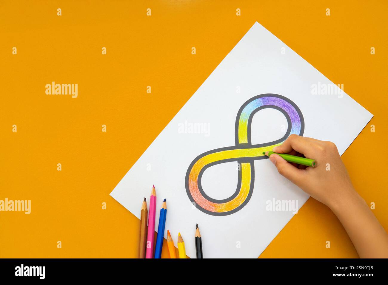 Une main coloriant un symbole d'infini arc-en-ciel sur une feuille de papier blanche avec des crayons de couleur dispersés autour. Concept de sensibilisation à l'autisme. Banque D'Images Une main coloriant un symbole d'infini arc-en-ciel sur une feuille de papier blanche avec des crayons de couleur dispersés autour. Concept de sensibilisation à l'autisme. Banque D'Images