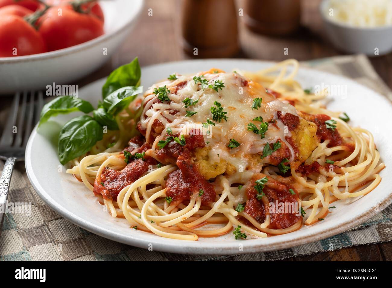 Poulet parmesan avec nouilles spaghetti et sauce garnie de feuilles de basilic et persil haché dans une assiette Banque D'Images