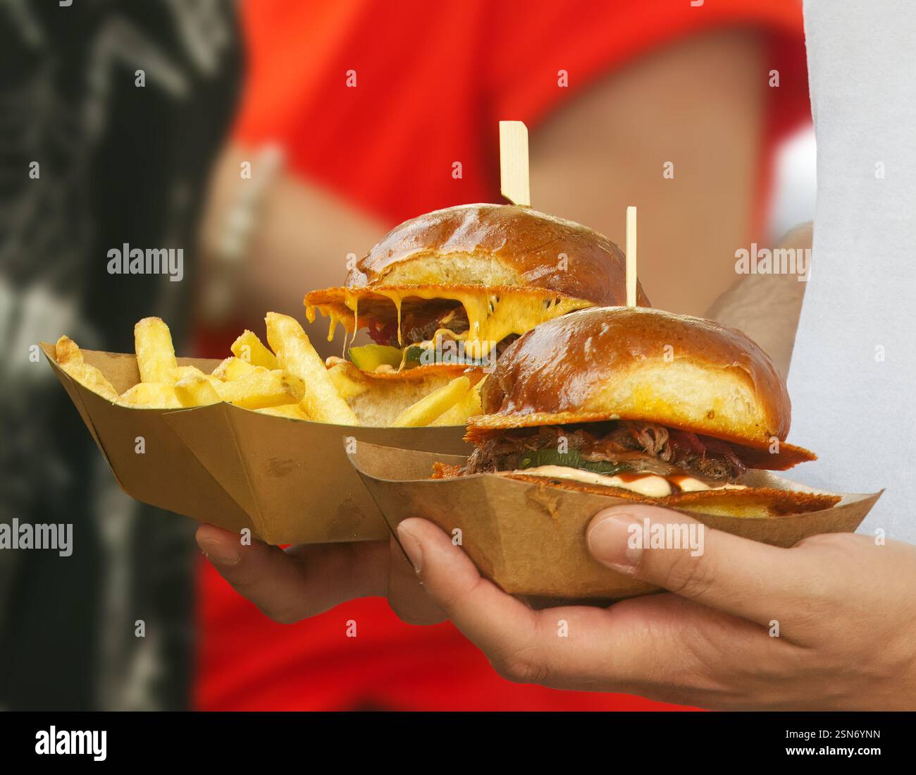 Gros plan de deux hamburgers au fromage fondu servis avec des frites dorées croustillantes. Une combinaison parfaite de délices de restauration rapide présentés dans un pack écologique Banque D'Images