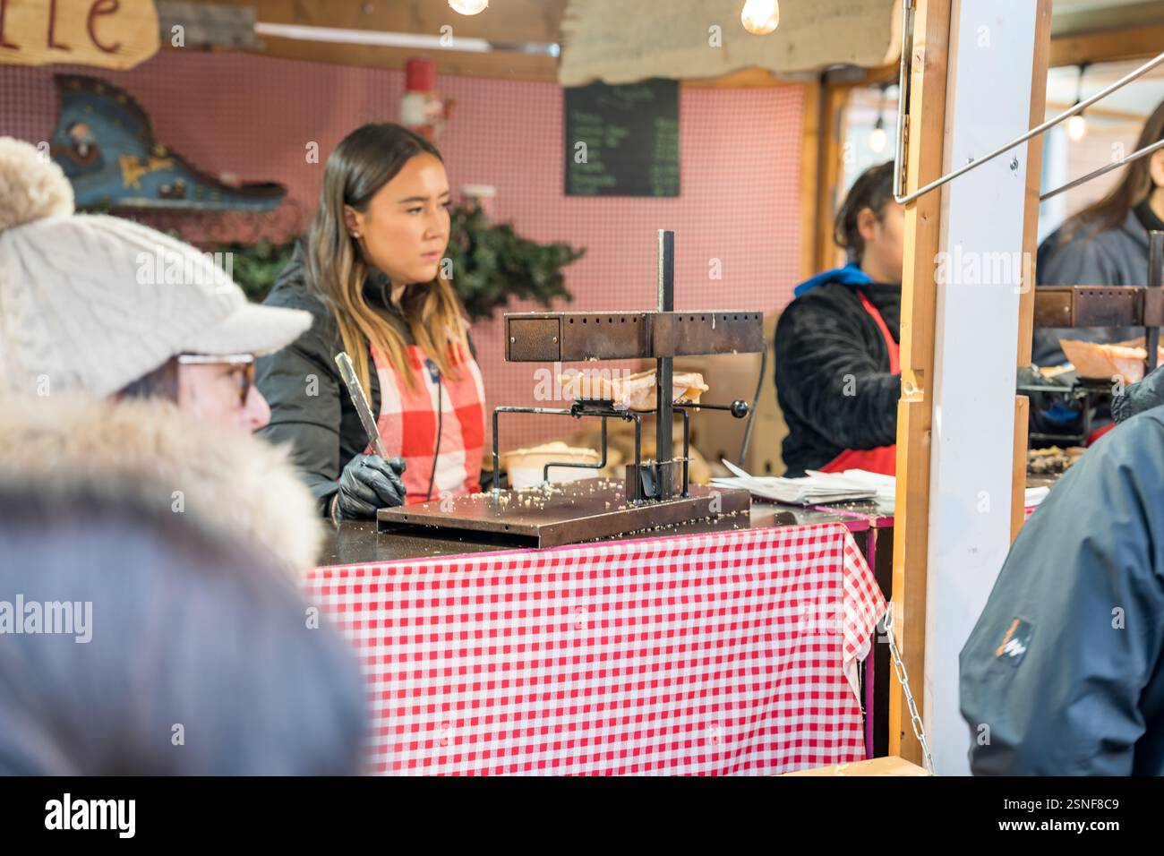 Un fournisseur qualifié prépare de délicieuses friandises sur un marché festif animé Banque D'Images