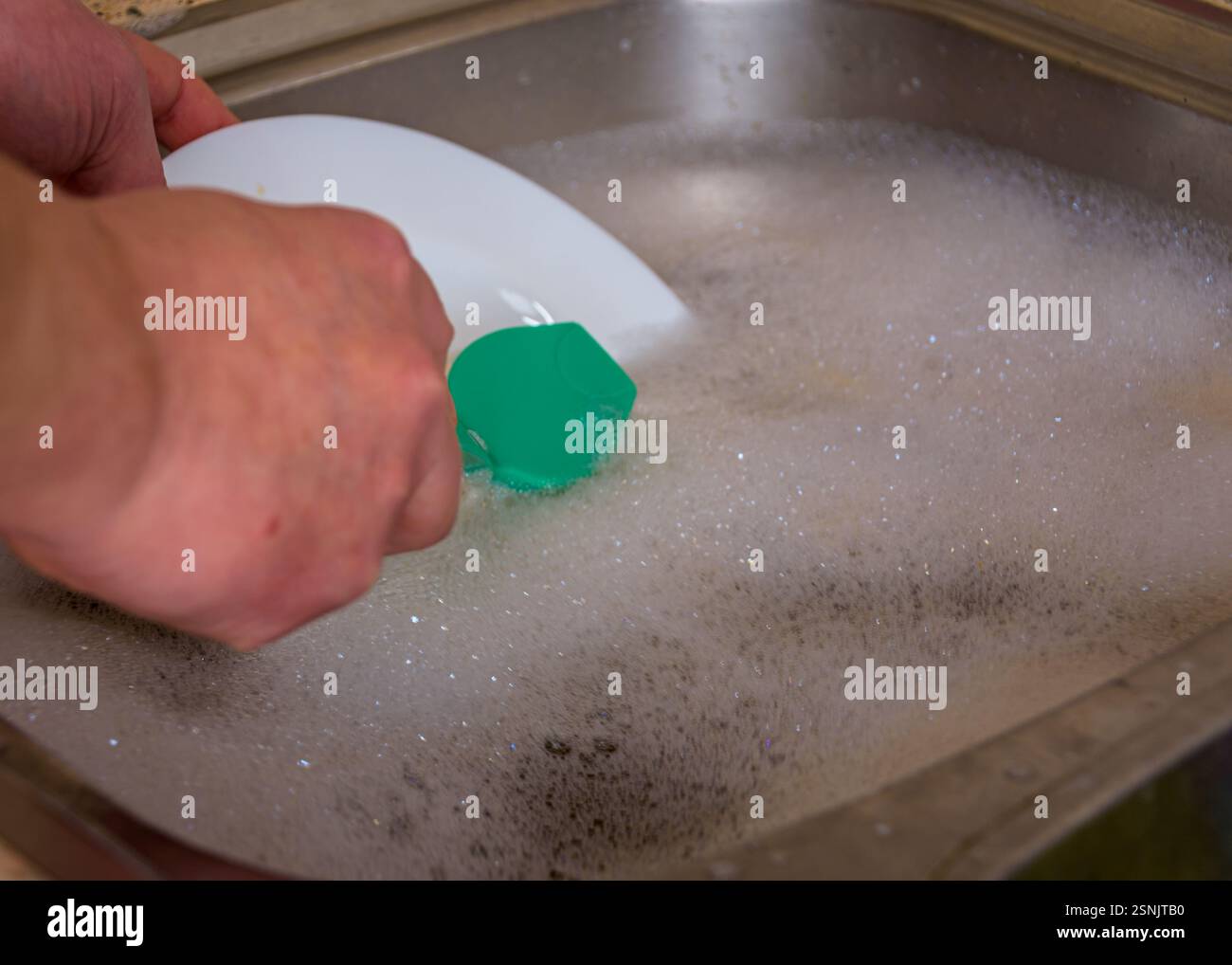 Laver la vaisselle à la main avec une éponge dans de l'eau savonneuse dans l'évier de cuisine Banque D'Images