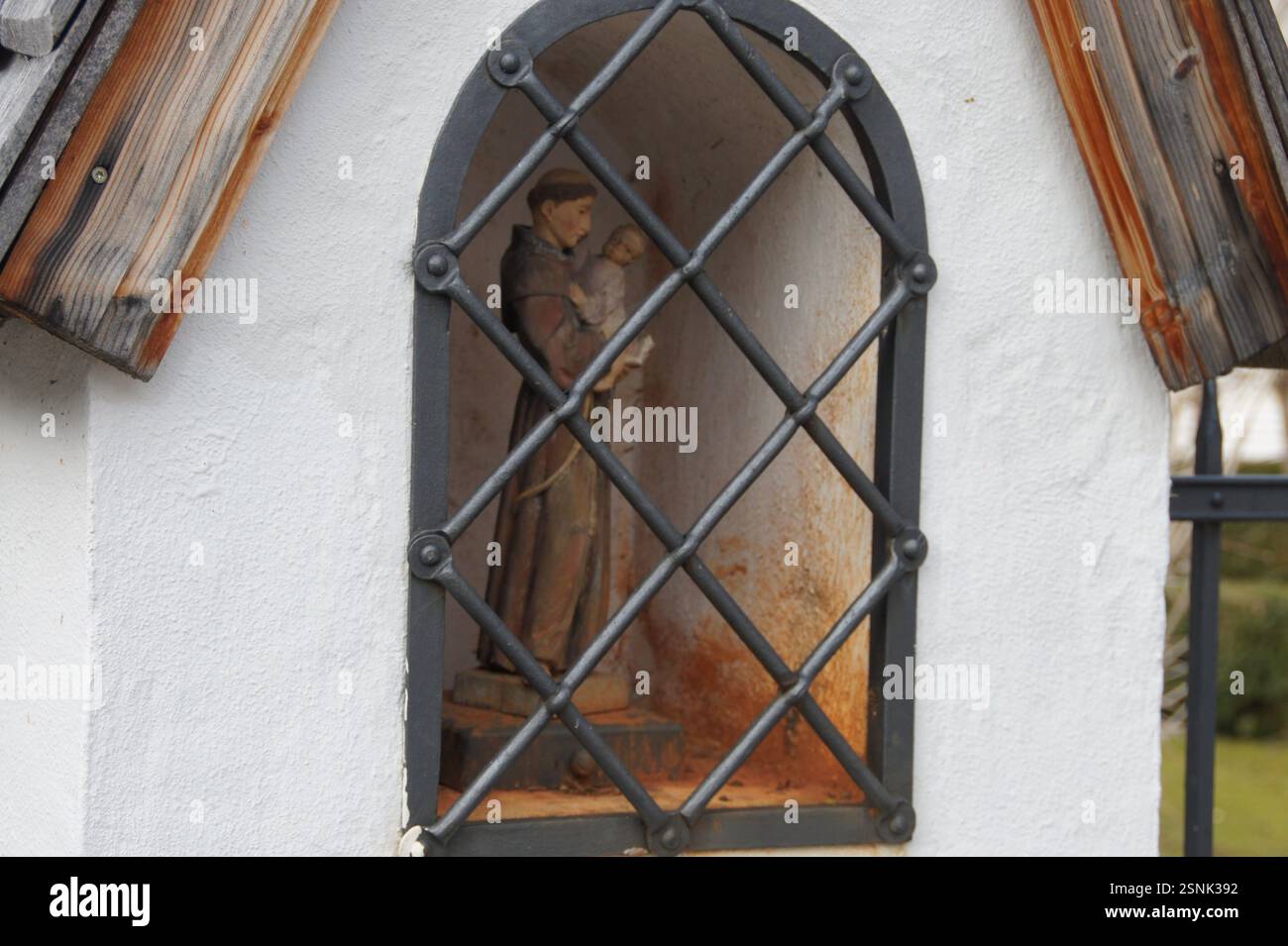 Statue en bois d'un homme tenant un bébé dans une fenêtre à cadre métallique à Munich, en Allemagne. La posture de l'homme suggère qu'il protège l'enfant. Le Banque D'Images