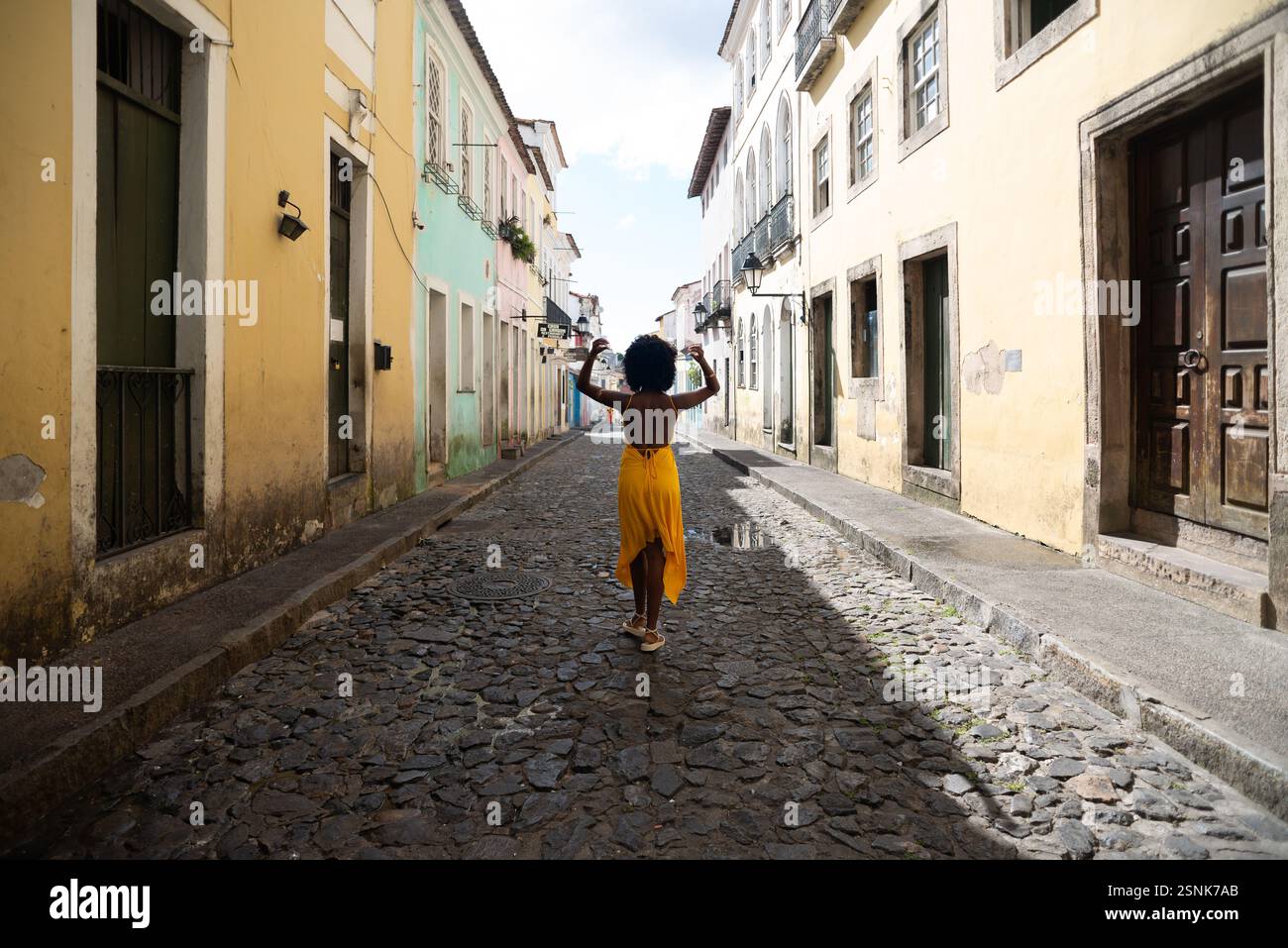 Portrait de belle femme portant une robe jaune debout sur la vieille rue pavée. Personne heureuse en voyage. Banque D'Images