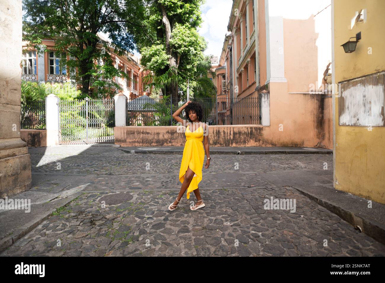 Portrait de belle femme portant une robe jaune debout sur la vieille rue pavée. Personne heureuse en voyage. Banque D'Images