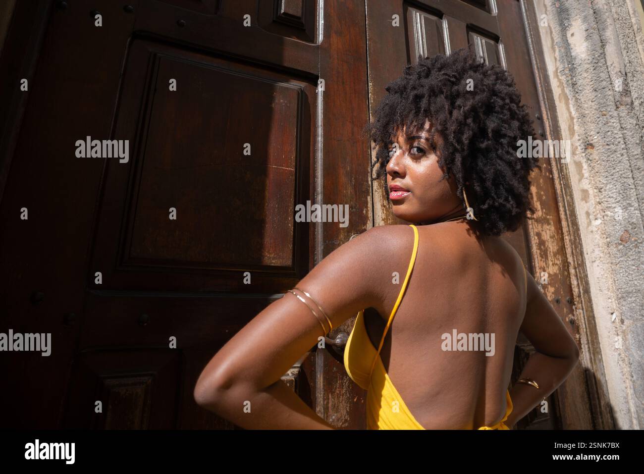 Portrait d'une belle femme portant une robe jaune debout par une vieille porte en bois brun. Concept de voyage de personne heureuse. Banque D'Images