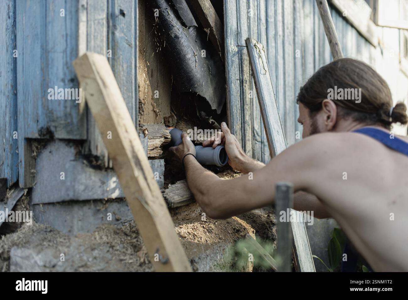 Homme insérant des tuyaux dans un mur extérieur, concentré sur la tâche Banque D'Images