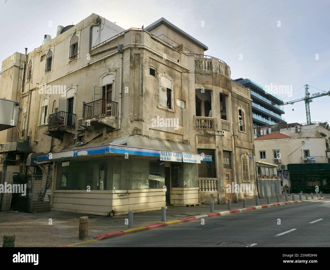 Un ancien bâtiment historique à rénover avec une construction d'un nouveau bâtiment résidentiel derrière elle. Hayarkon Street, tel Aviv, Israël. - Image de stock capturée avec un smartphone
