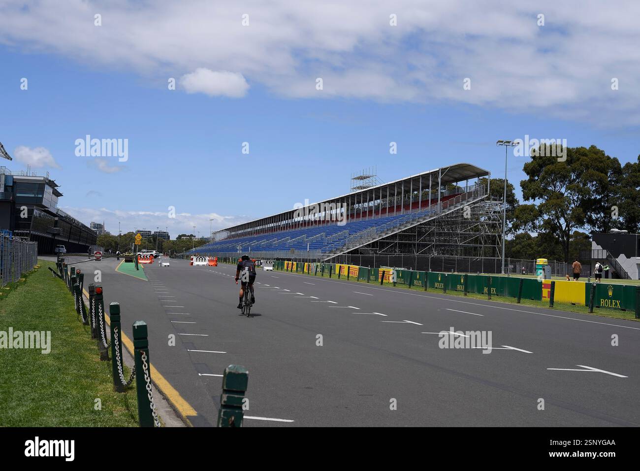 Un cycliste longe le départ et l'arrivée du circuit de formule 1 de Melbourne avant le Grand Prix avec les tribunes en construction. Banque D'Images
