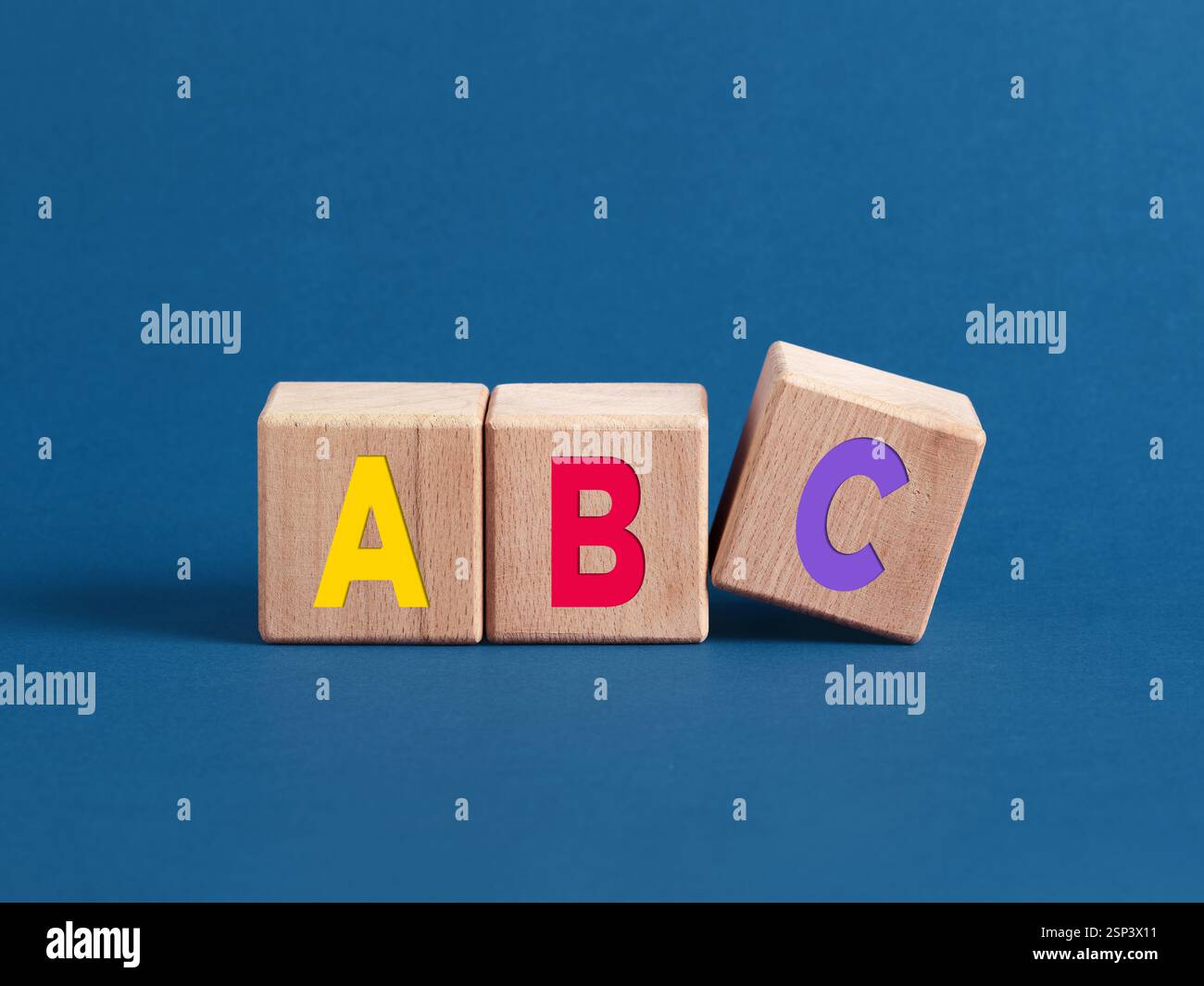 Les lettres colorées abc sont écrites sur des cubes de bois, avec la lettre c tombant, représentant l'éducation et l'apprentissage de la petite enfance Banque D'Images