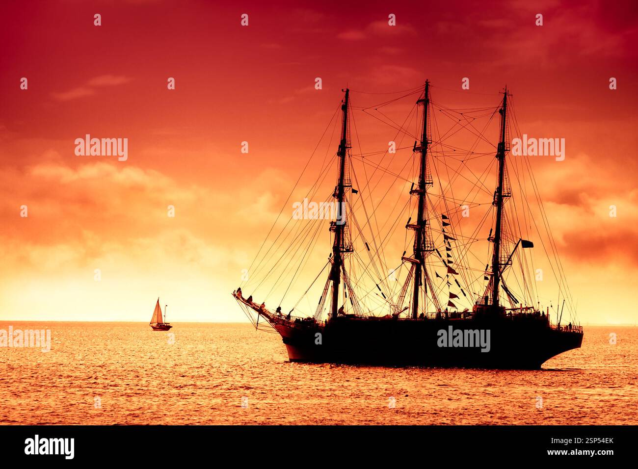 Grand voilier noir sur la haute mer au crépuscule. Hollandais volant au coucher de soleil rouge ambre Banque D'Images