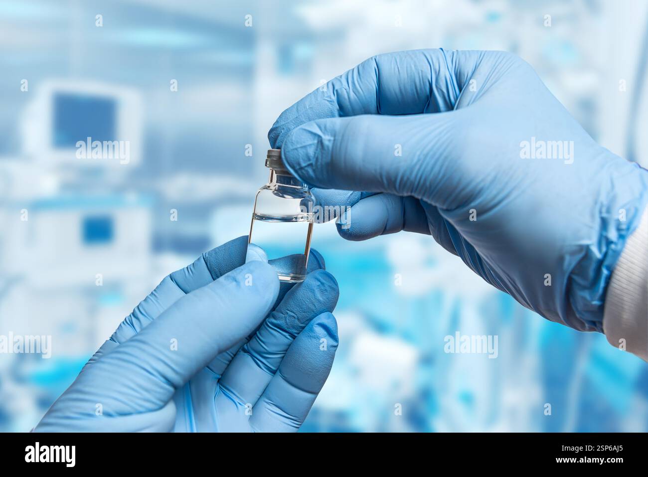 Un professionnel de la santé portant des gants bleus tient soigneusement un petit flacon transparent de liquide tout en se préparant à une intervention médicale dans un cadre clinique. Banque D'Images