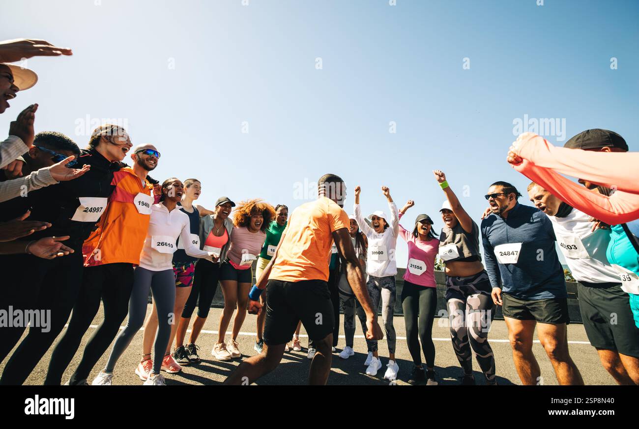 Une scène vibrante capture un chef d'équipe énergisant les membres du groupe avant une course. Les participants se rencontrent, exprimant leur enthousiasme et leur soutien. Ceci i Banque D'Images