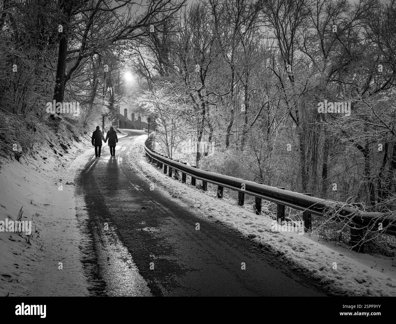 Homme et femme marchant vers le haut de la colline avec de la neige dans le froid d'hiver, Pennsylvanie USA Banque D'Images