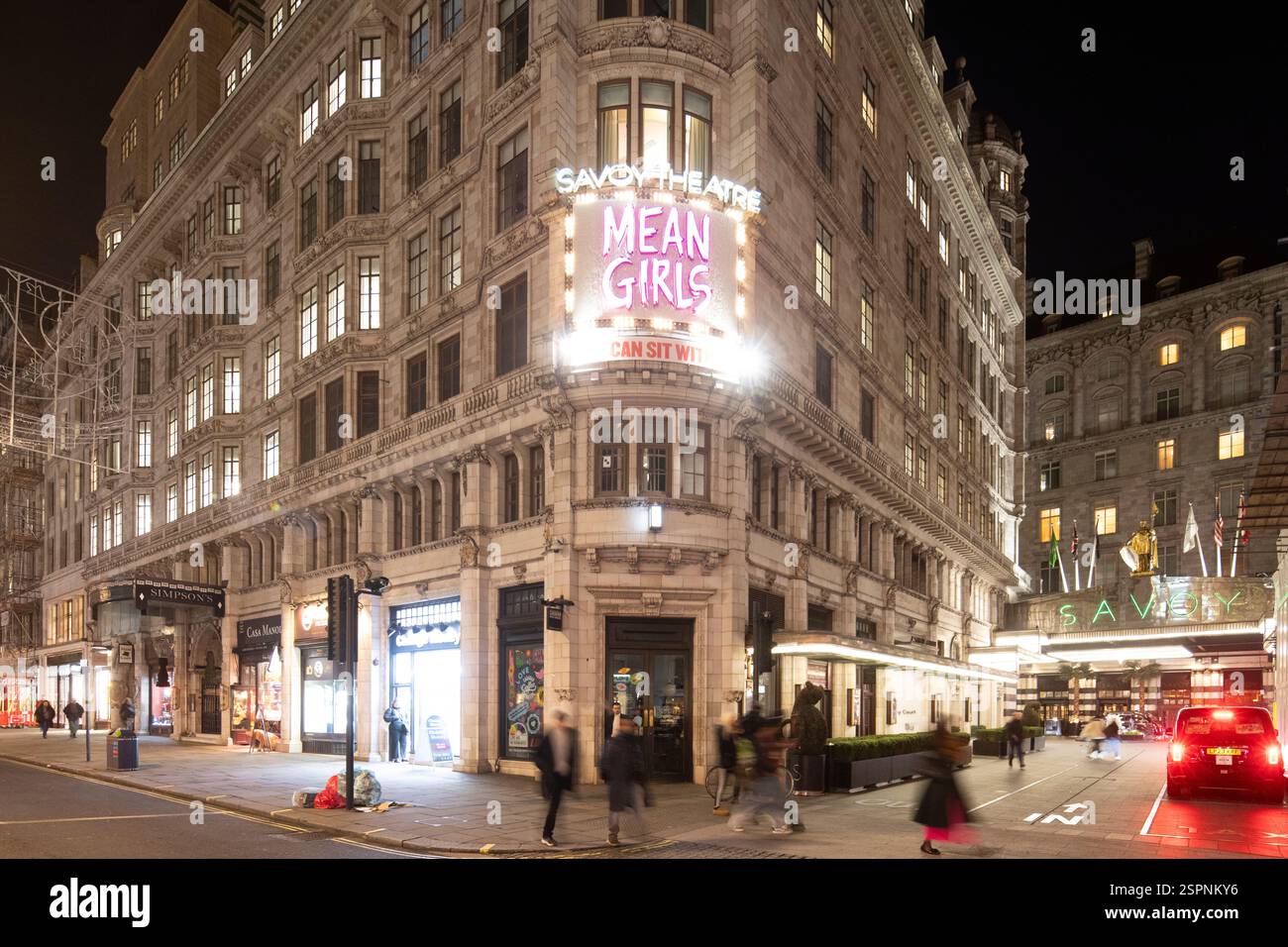 Vue nocturne du Savoy Theatre and Hotel, Londres. Affiche « Mean Girls » visible au Savoy Theatre. Des piétons et une voiture sont dans la rue. Banque D'Images