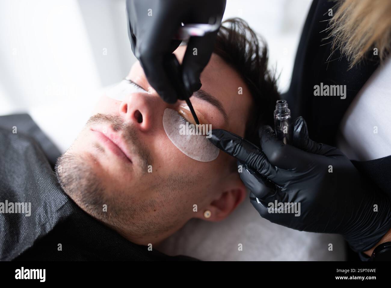 Un jeune homme dans un salon de beauté prenant soin des cils. Banque D'Images