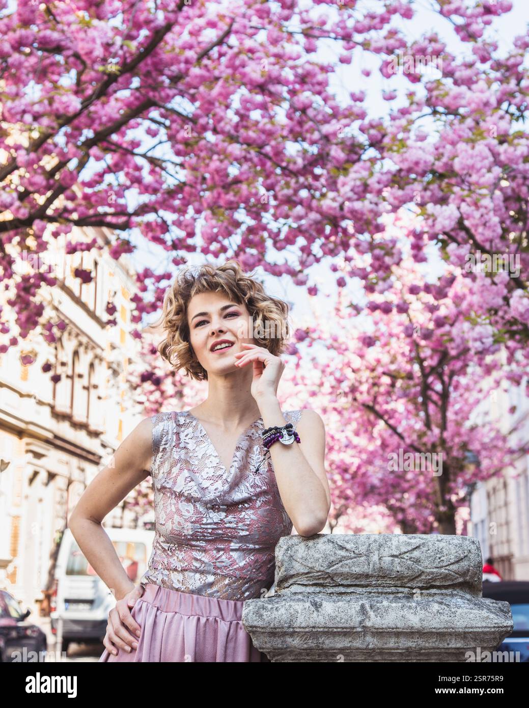 Élégante belle femme posant dans une tenue décente avec des arbres de fleurs de cerisier en arrière-plan. Elle a l'air rêveuse et très confiante. Loin de l'appareil photo Banque D'Images