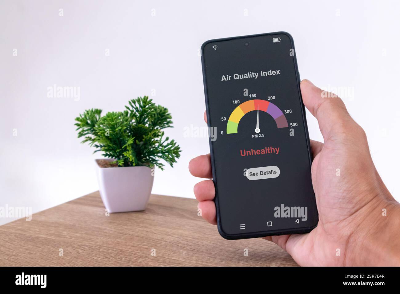 Homme dans la chambre vérifiant l'indice de qualité de l'air à l'aide d'un smartphone Banque D'Images
