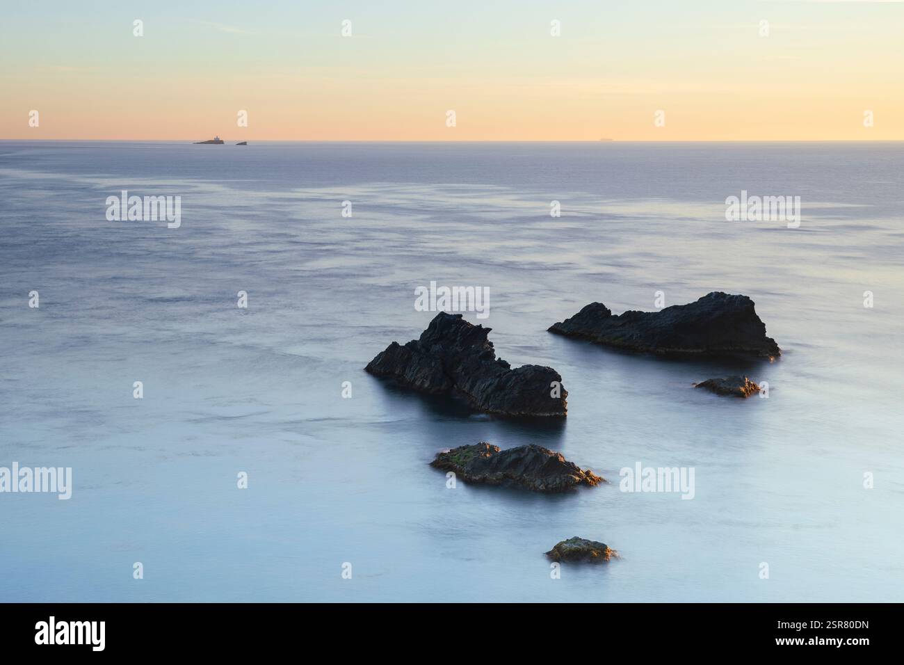 Lever de soleil doux sur la mer Méditerranée à Cabo de Palos, Carthagène, région de Murcie, Espagne, avec des roches volcaniques émergeant de l'eau bleue calme Banque D'Images
