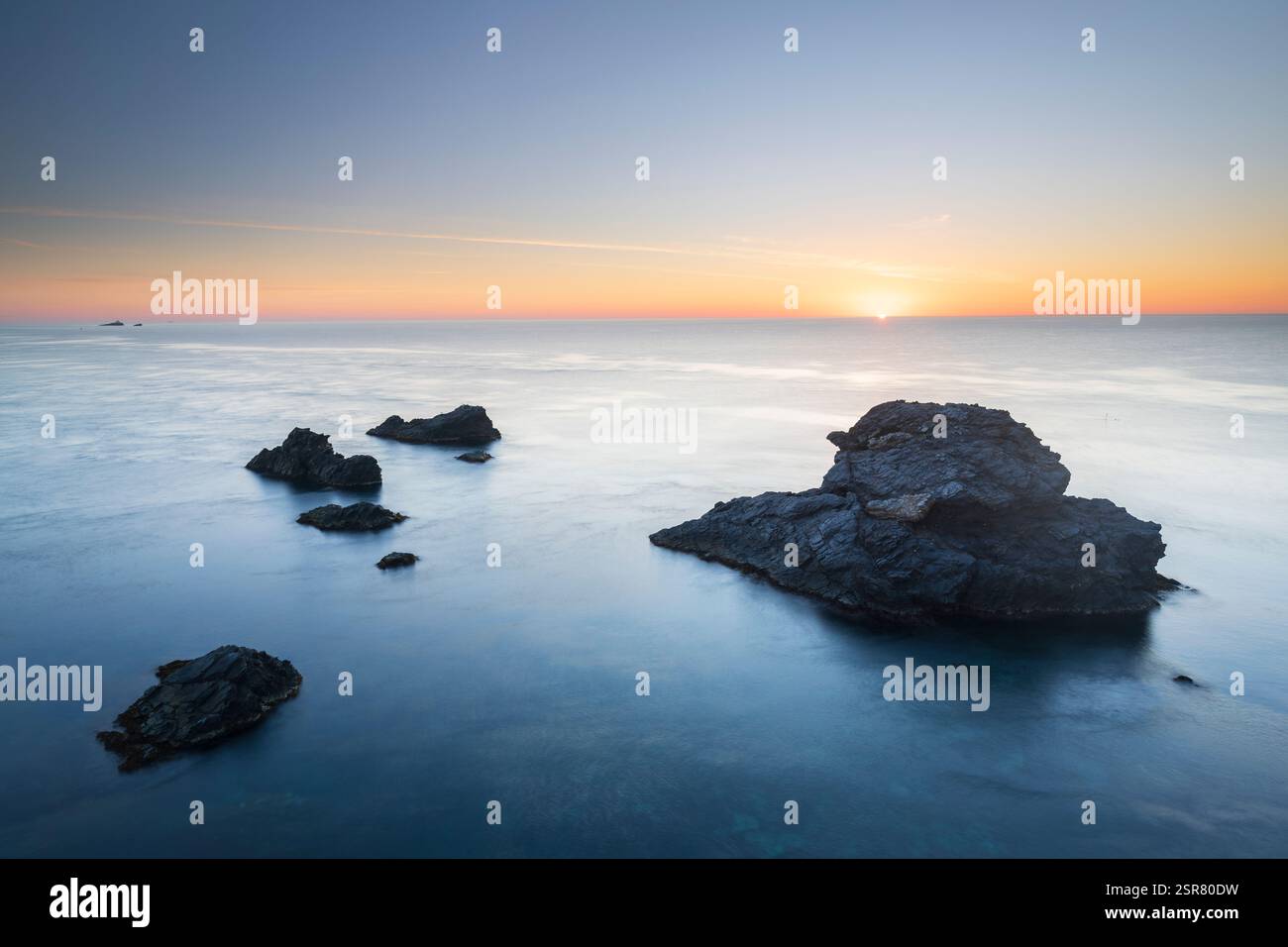 Lever de soleil sur la mer Méditerranée à Cabo de Palos, Carthagène, région de Murcie, Espagne, avec des roches volcaniques émergeant des eaux bleues calmes Banque D'Images
