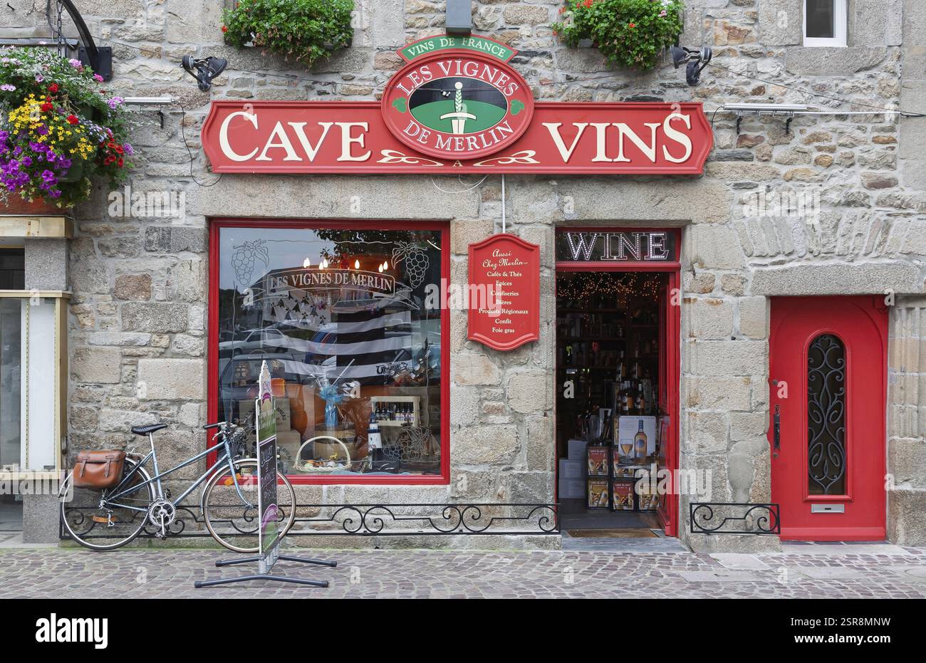 Magasin de vin français avec des accents rouges et façade de maison en pierre, décoré de fleurs et d'un vélo en face, Roscoff, Bretagne, France, Europe Banque D'Images