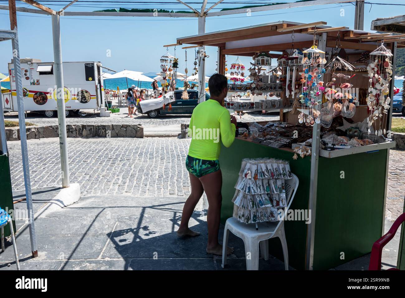 Étal de rue dynamique vendant des souvenirs près de la plage de Prainha sur l'avenue Alfredo Dante Fassini sous un ciel bleu clair et ensoleillé matin d'été. Banque D'Images