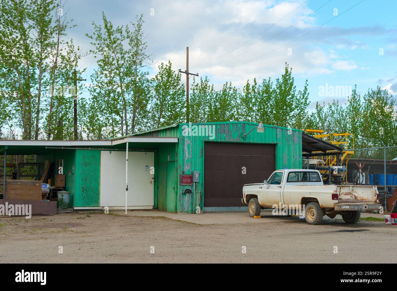 Vieux garage en métal vert, atelier avec camionnette blanche garé à l'extérieur à Galena, Alaska, USA Banque D'Images