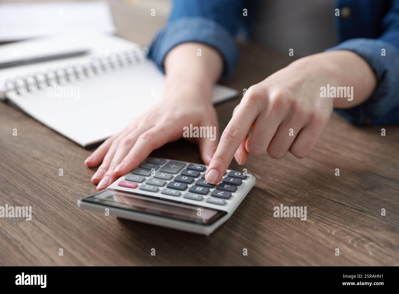 Budget. Femme avec la paperasse et la calculatrice au bureau en bois à l'intérieur, gros plan Banque D'Images