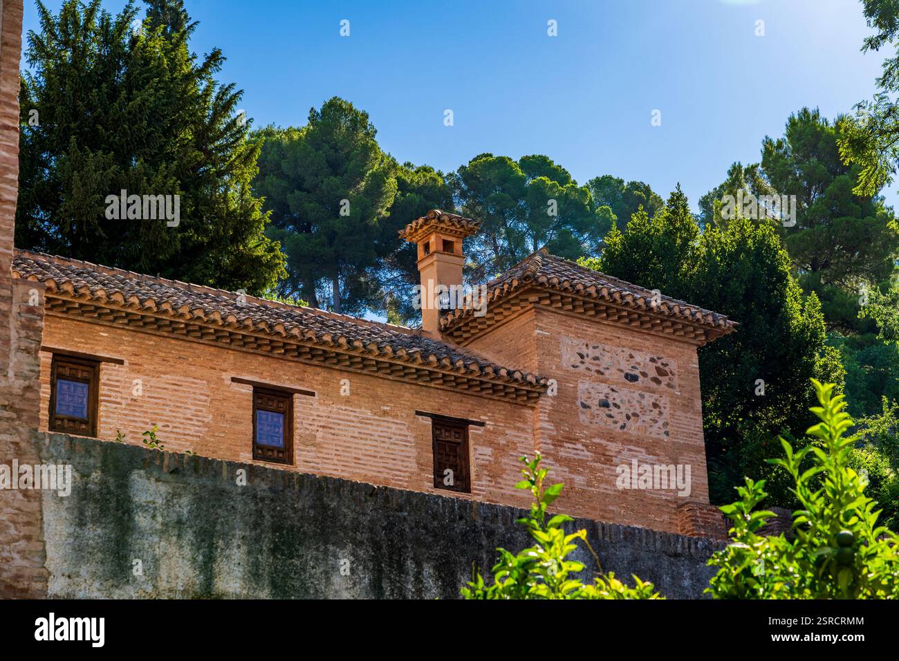 Briques andalouses baignées de soleil de Casa de los Amigos dans l'Alhambra sous des pins verdoyants Banque D'Images