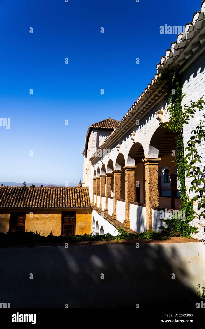 Les arches ensoleillées de la cour Generalife de l'Alhambra avec des toits en terre cuite et Ivy contre un ciel bleu brillant Banque D'Images
