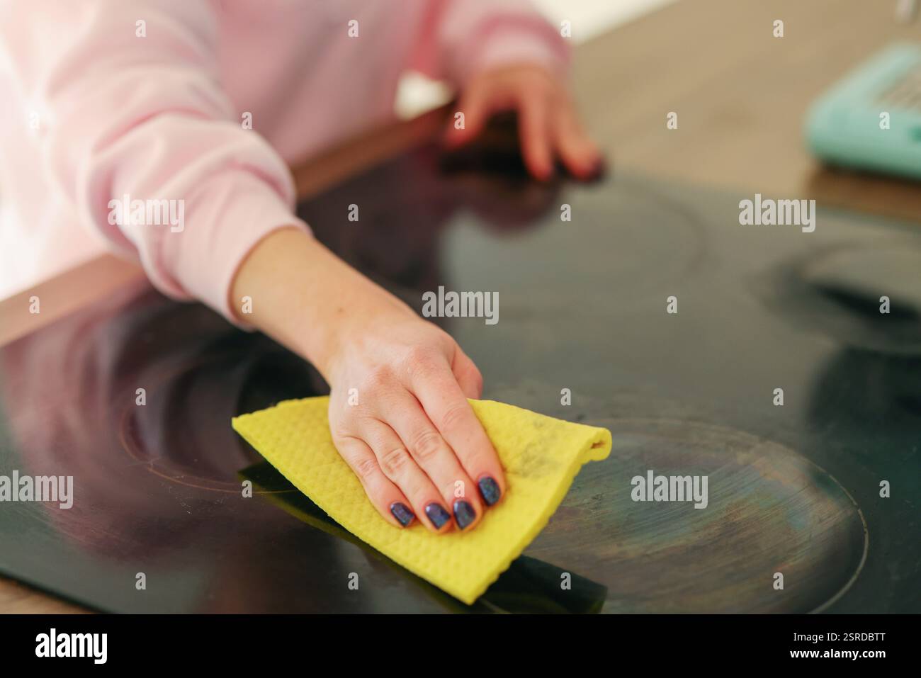 une fille en gants de caoutchouc jaunes lave une cuisinière électrique Banque D'Images