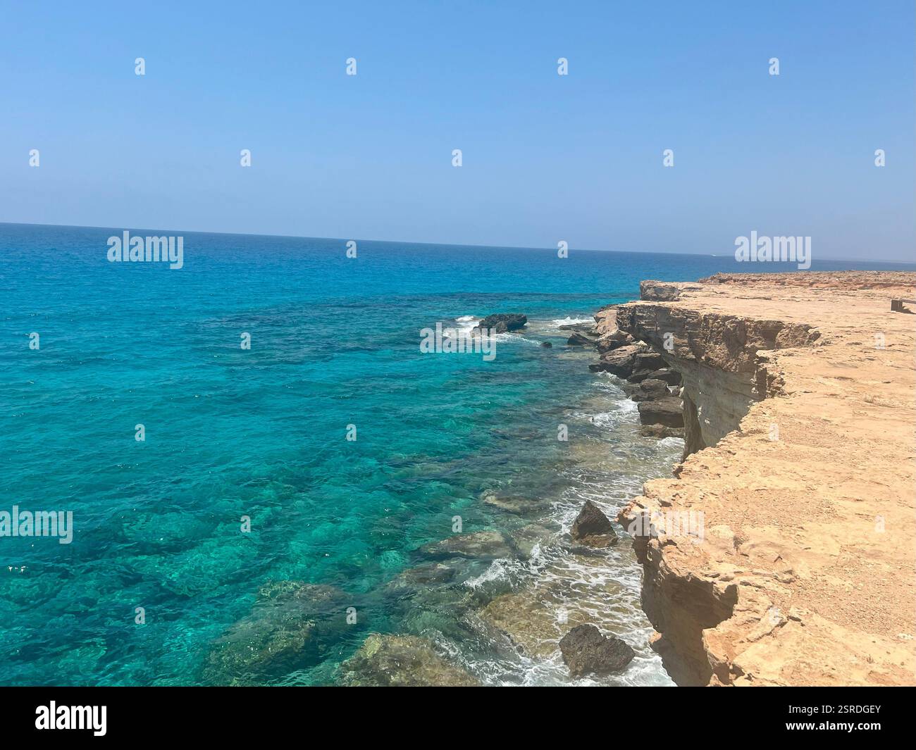 Vue imprenable depuis une falaise à Chypre, surplombant la mer turquoise cristalline et la côte accidentée, mettant en valeur la beauté de la Méditerranée - Image de stock capturée avec un smartphone