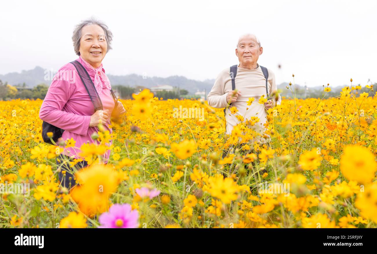 Heureux couple aîné randonnée sur le sentier par des plantes de fleurs au printemps Banque D'Images