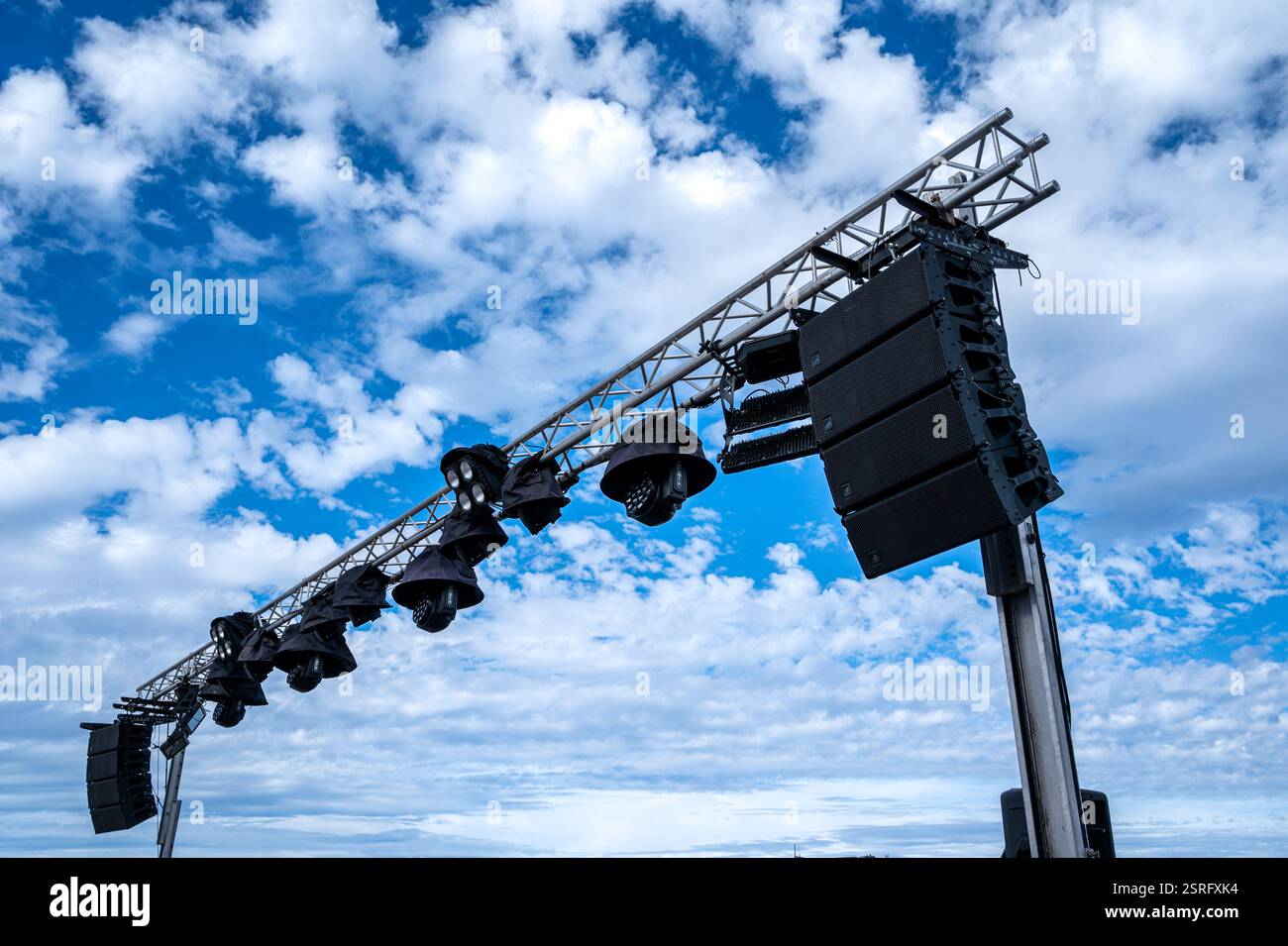 Un grand ensemble de lumières est suspendu à un poteau métallique. Le ciel est nuageux et le soleil brille à travers les nuages Banque D'Images