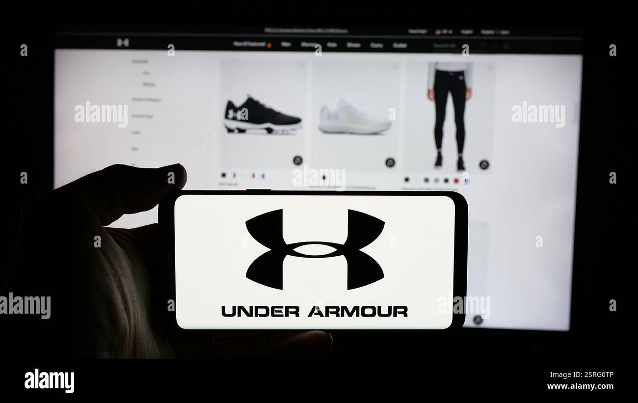Allemagne. 15 janvier 2025. Dans cette illustration photo, une personne tient un téléphone portable avec le logo de la société américaine de vêtements de sport Under Armour Inc sur l'écran devant la page Web de l'entreprise. Crédit : SOPA images Limited/Alamy Live News Banque D'Images