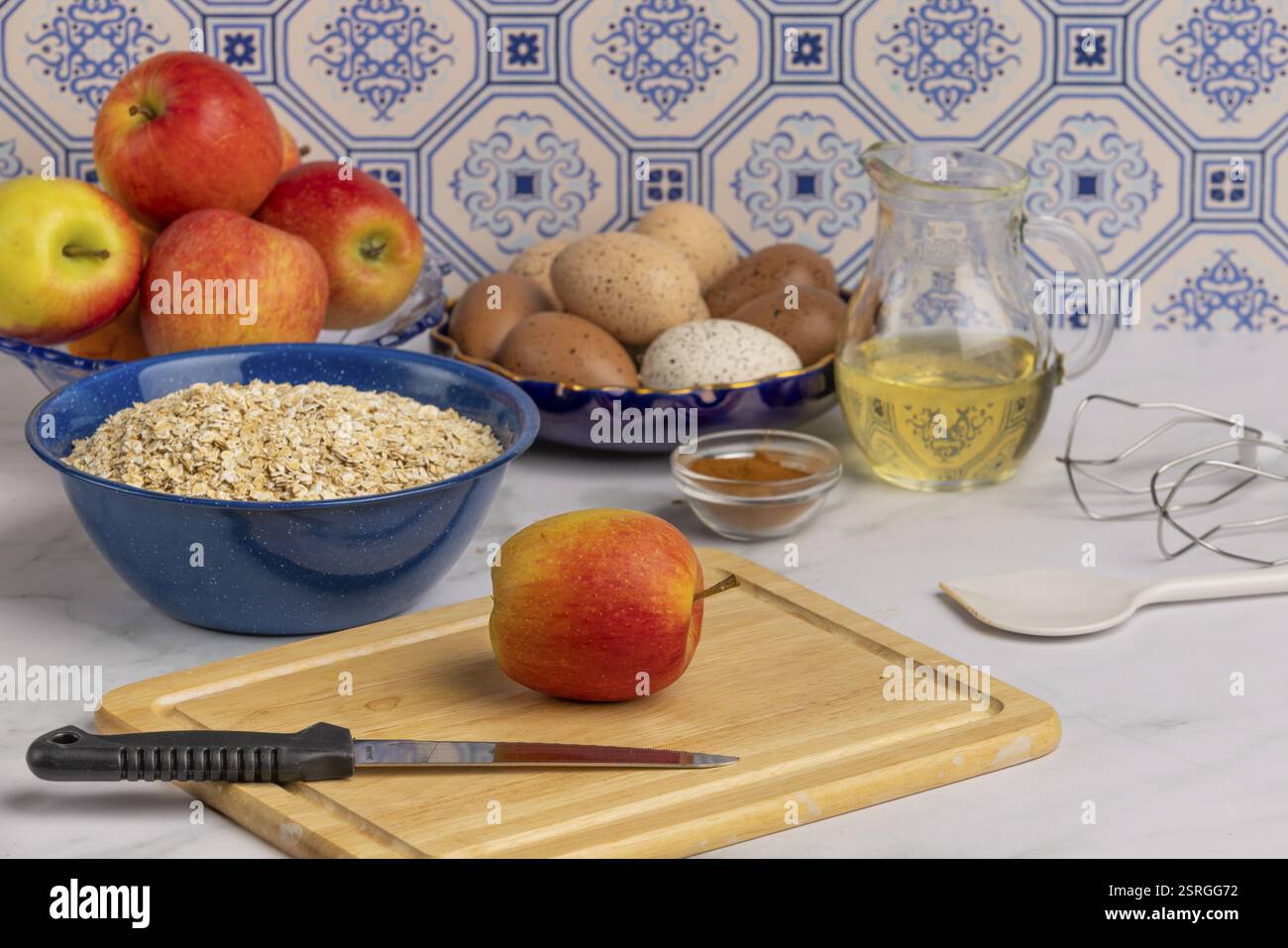 Une préparation de cuisson avec pommes, œufs, flocons d'avoine, cannelle et accessoires Banque D'Images