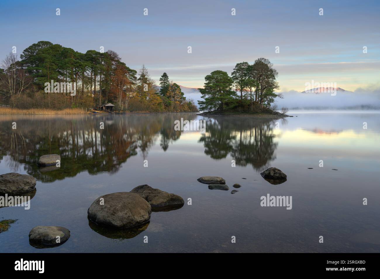 Réflexions calmes sur un matin brumeux à Derwentwater dans le Lake District, Royaume-Uni. Banque D'Images