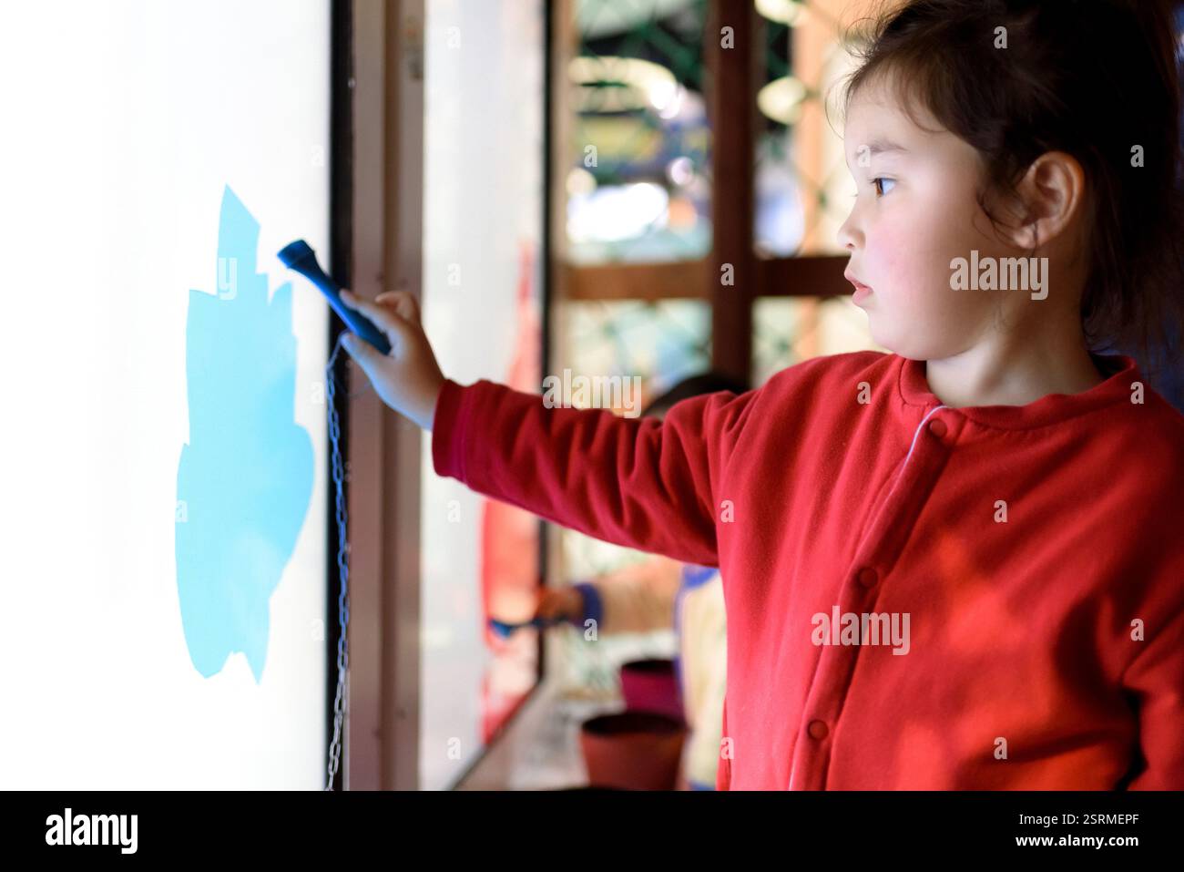 Fille chinoise de quatre ans dessinant avec brosse digitaliser sur tableau blanc interactif électronique dans le musée technologique de Nanchang, . Banque D'Images